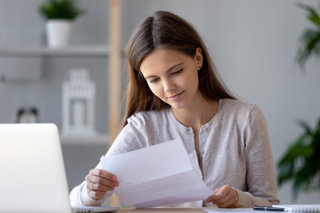 woman sitting at a desk and reading a document while smiling