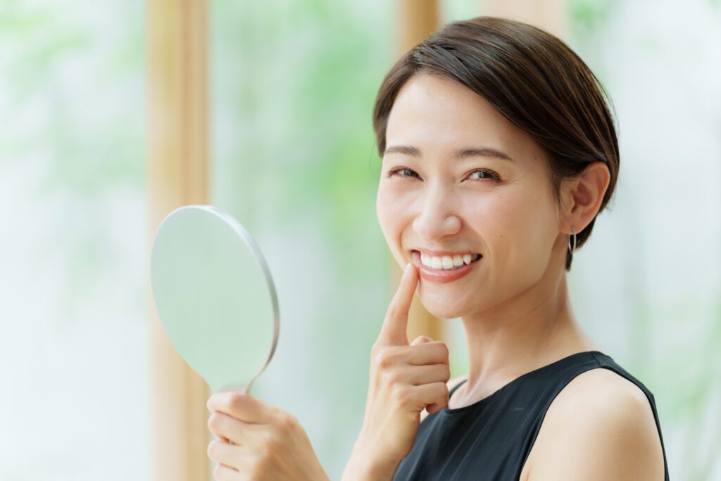 woman smiling and holding up mirror