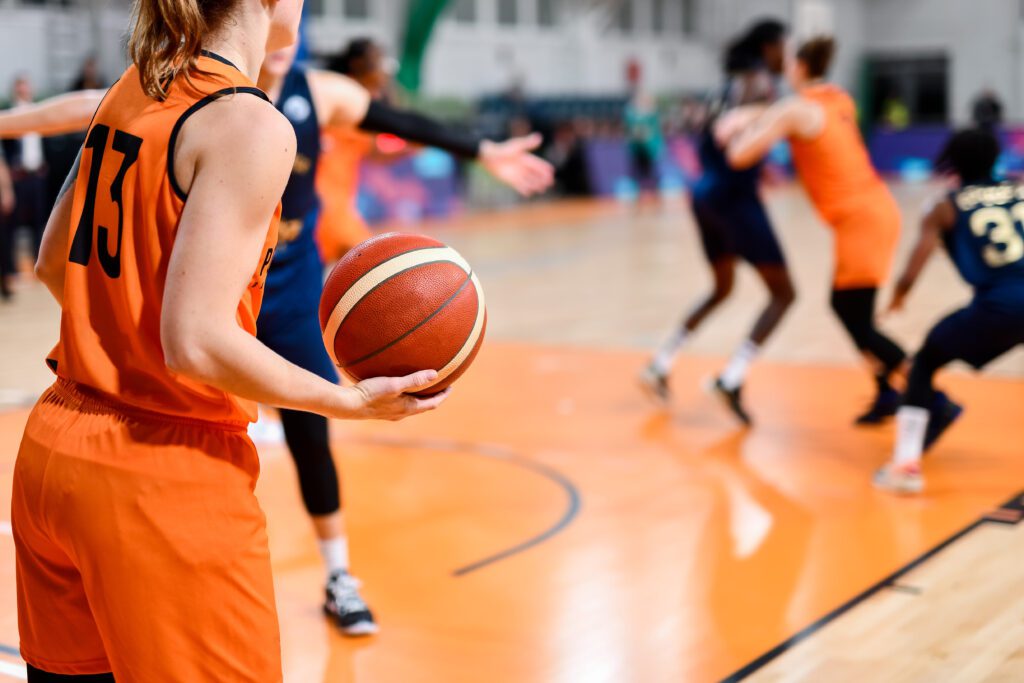 Woman player keeps the ball during basketball match.