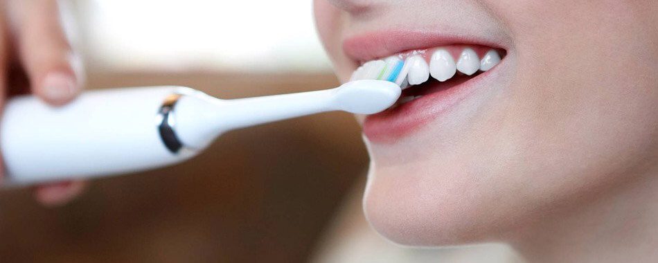 woman brushing teeth with sonicare toothbrush